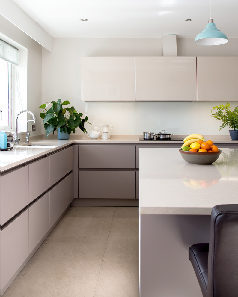 Design ideas for a contemporary kitchen in Dublin with flat-panel cabinets, quartzite benchtops, glass sheet splashback, panelled appliances, porcelain floors and with island.