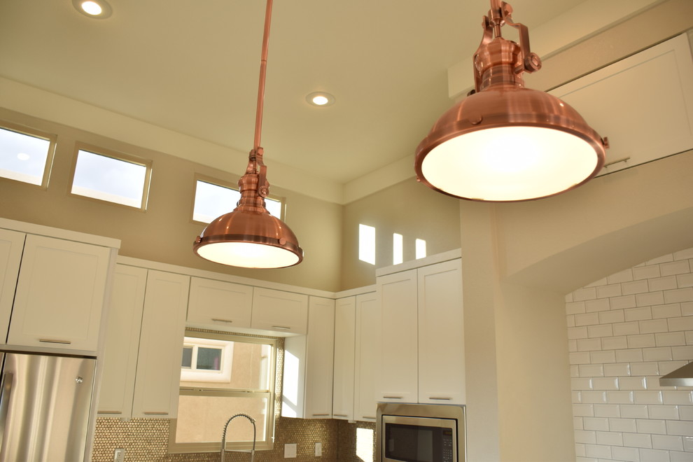 Transitional home design photo in Austin with quartzite countertops, white cabinets, white backsplash, subway tile backsplash and stainless steel appliances