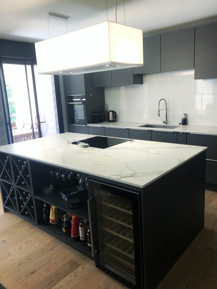 Inspiration for a large contemporary l-shaped kitchen/diner in Toulouse with an integrated sink, beaded cabinets, stainless steel cabinets, quartz worktops, white splashback, glass tiled splashback, coloured appliances, light hardwood flooring, an island, brown floors and white worktops.