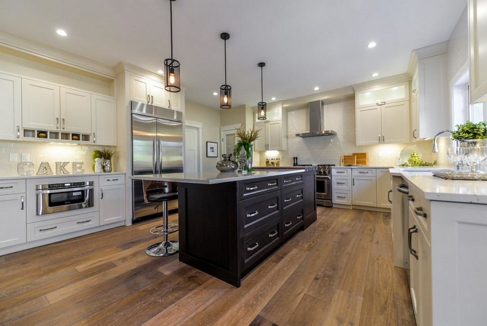 Open concept kitchen - large transitional u-shaped medium tone wood floor and brown floor open concept kitchen idea in Edmonton with an undermount sink, shaker cabinets, white cabinets, quartz countertops, white backsplash, subway tile backsplash, stainless steel appliances and an island