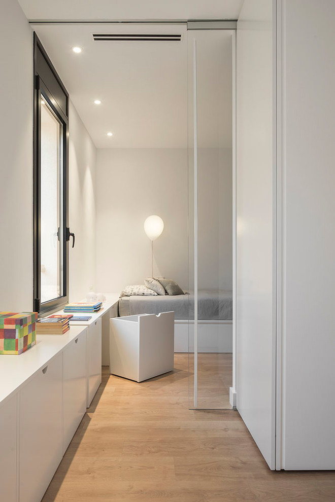 Design ideas for a mid-sized contemporary gender-neutral kids' playroom for kids 4-10 years old in Barcelona with white walls, medium hardwood floors and brown floor.