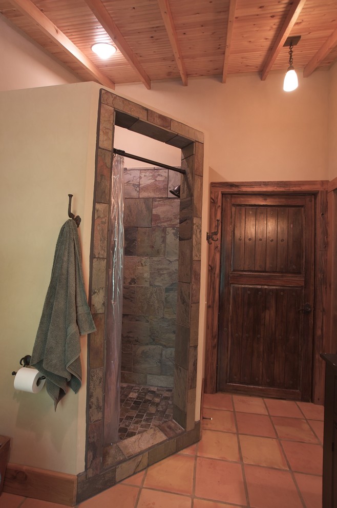 Inspiration for a large rustic master terra-cotta tile corner shower remodel with recessed-panel cabinets, black cabinets, beige walls, a vessel sink and solid surface countertops