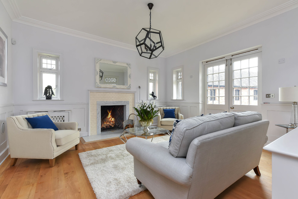 Mid-sized transitional enclosed living room in Other with blue walls, medium hardwood floors, a standard fireplace and brown floor.
