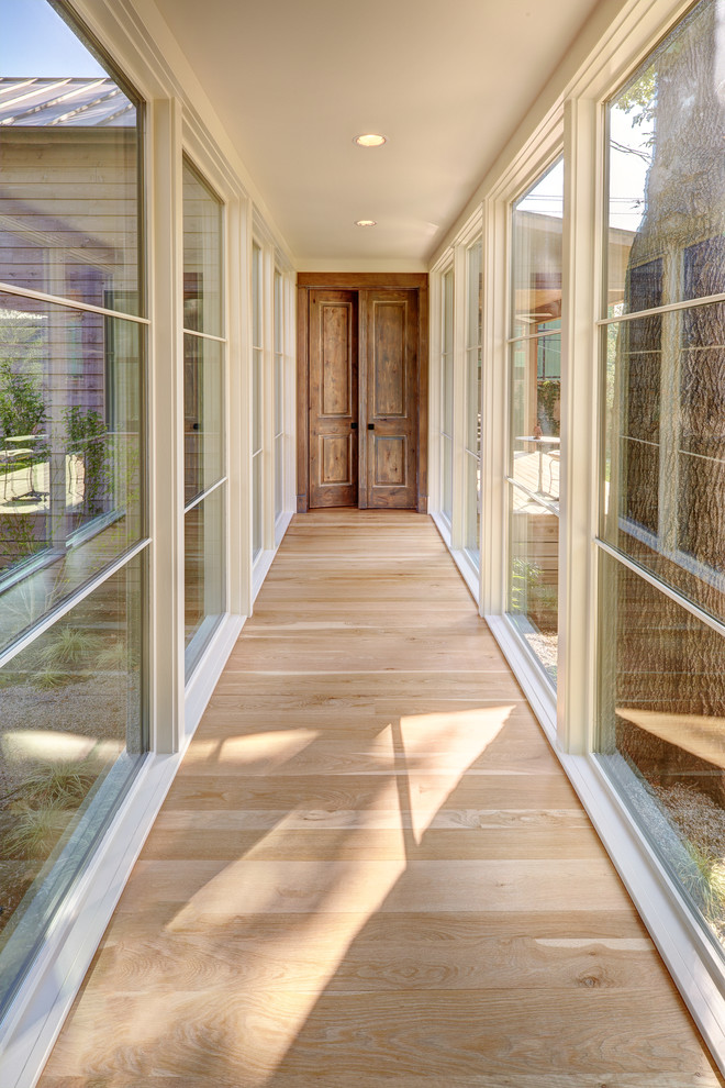 Design ideas for a large transitional hallway in Austin with white walls, light hardwood floors and beige floor.