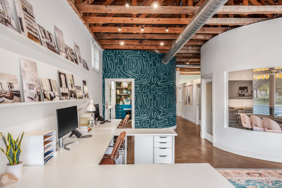 Klassisches Arbeitszimmer mit weißer Wandfarbe, Betonboden, freistehendem Schreibtisch, braunem Boden, freigelegten Dachbalken und Tapetenwänden in Austin