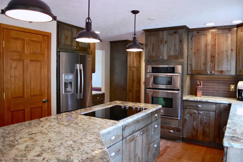 Eat-in kitchen - mid-sized rustic l-shaped light wood floor eat-in kitchen idea in New York with shaker cabinets, medium tone wood cabinets, granite countertops, brown backsplash, ceramic backsplash, stainless steel appliances, an island and an undermount sink
