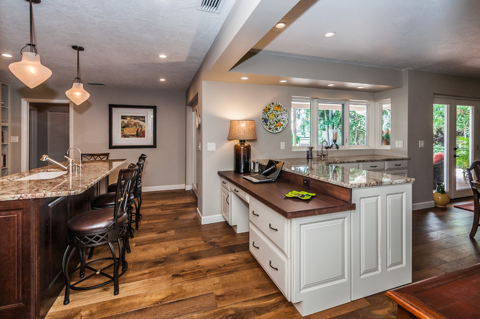 Open concept kitchen - traditional u-shaped open concept kitchen idea in Tampa with an undermount sink, raised-panel cabinets, beige cabinets, granite countertops, white backsplash, subway tile backsplash and paneled appliances