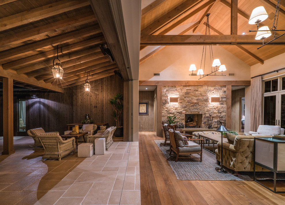 This is an example of a large country open concept living room in San Francisco with white walls, medium hardwood floors, a standard fireplace, a stone fireplace surround and no tv.