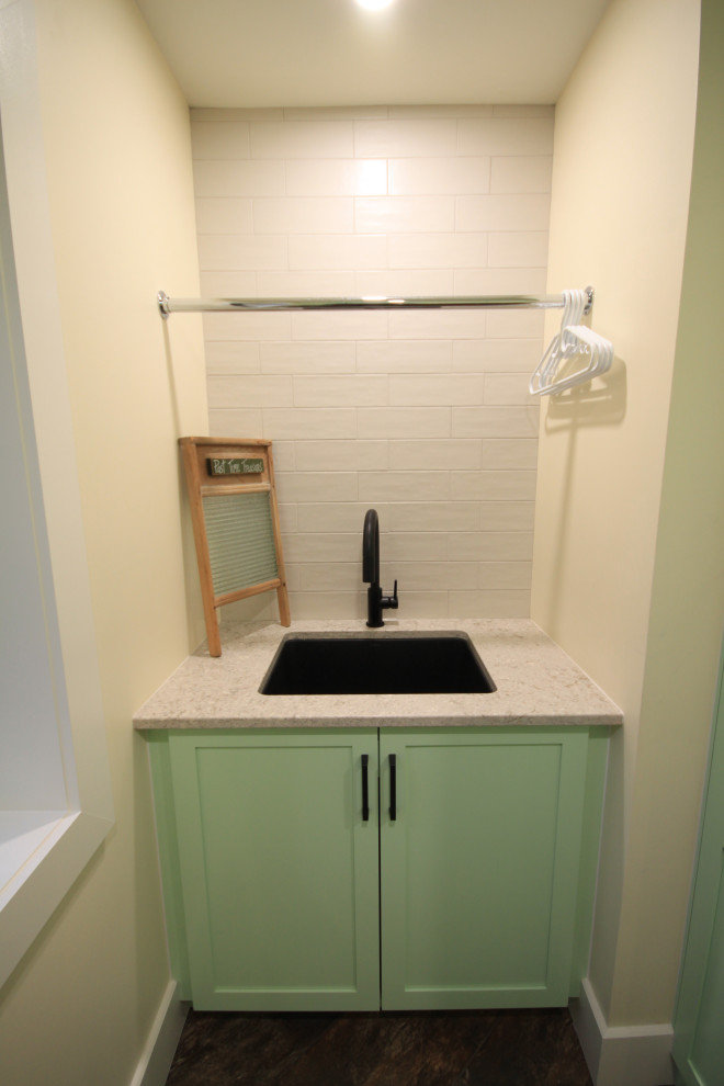 Modern inredning av en stor gröna parallell grönt tvättstuga enbart för tvätt, med en undermonterad diskho, skåp i shakerstil, gröna skåp, bänkskiva i koppar, vitt stänkskydd, stänkskydd i tunnelbanekakel, vita väggar, vinylgolv, en tvättmaskin och torktumlare bredvid varandra och brunt golv