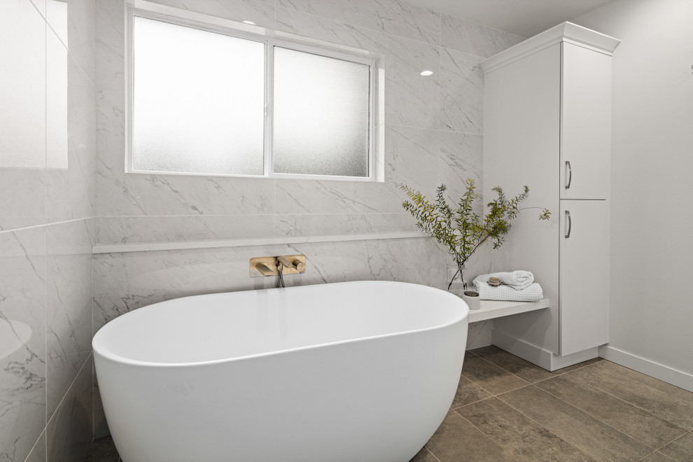 Inspiration for a large contemporary ensuite bathroom in Seattle with flat-panel cabinets, white cabinets, a freestanding bath, a built-in shower, a bidet, white tiles, marble tiles, white walls, porcelain flooring, a submerged sink, engineered stone worktops, grey floors, an open shower, white worktops, a wall niche, double sinks and a built in vanity unit.