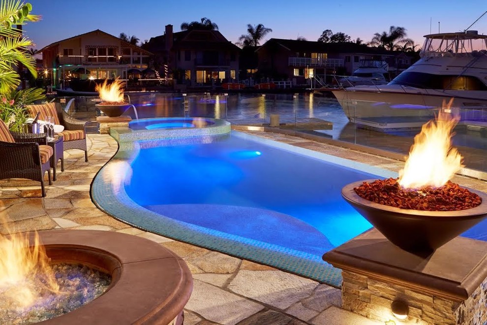 Hot tub - mid-sized transitional backyard stone and custom-shaped infinity hot tub idea in Orange County