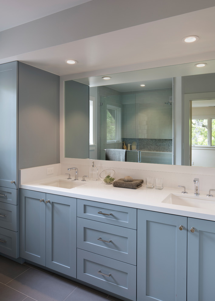 Inspiration for a mid-sized transitional kids bathroom in San Francisco with shaker cabinets, blue cabinets, a one-piece toilet, white tile, ceramic tile, white walls, an undermount sink, solid surface benchtops, porcelain floors, grey floor and a hinged shower door.