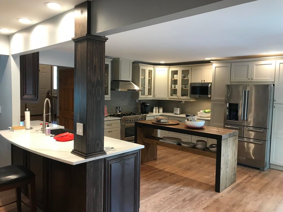 Example of a mountain style l-shaped light wood floor and brown floor eat-in kitchen design in Chicago with a single-bowl sink, shaker cabinets, gray cabinets, quartz countertops, stainless steel appliances, an island and white countertops