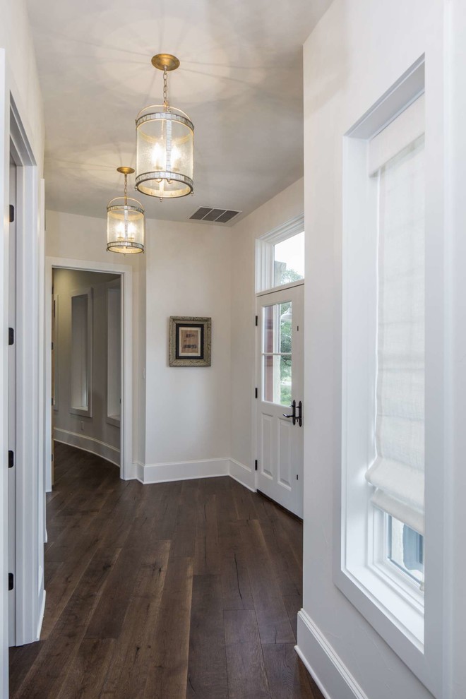 Photo of a mid-sized country hallway in Austin with white walls, dark hardwood floors and brown floor.