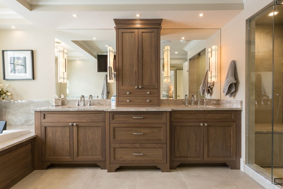Photo of a large traditional master bathroom in Calgary with recessed-panel cabinets, dark wood cabinets, a drop-in tub, an alcove shower, multi-coloured tile, ceramic tile, beige walls, ceramic floors, an undermount sink, marble benchtops and grey benchtops.