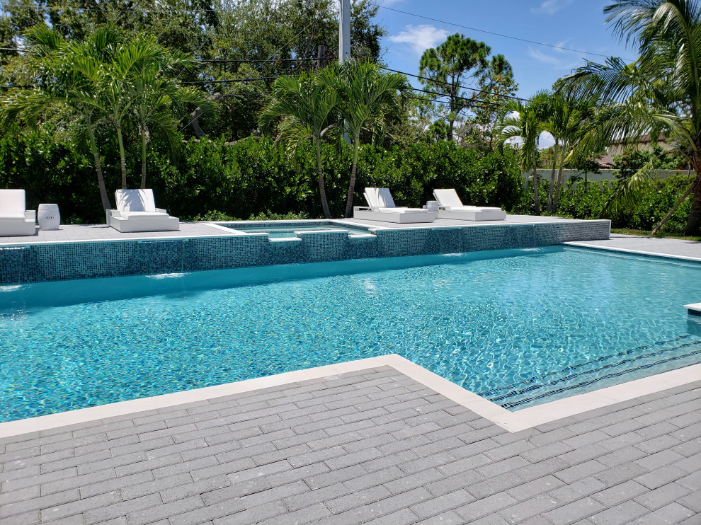 This is an example of a large mediterranean backyard custom-shaped pool in Other with a hot tub and brick pavers.