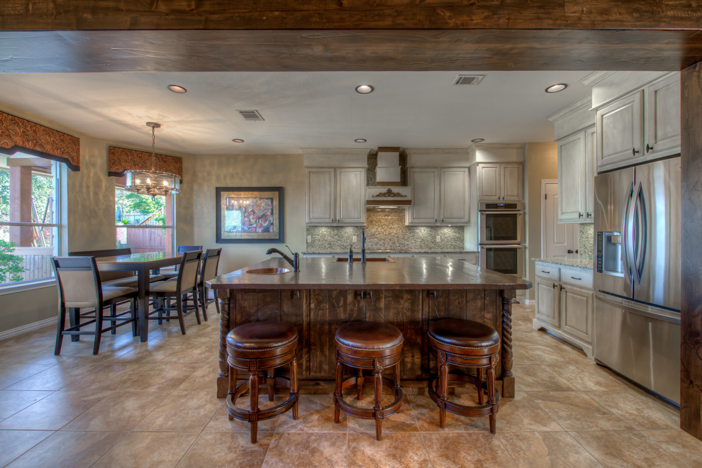 Example of a mid-sized mountain style l-shaped eat-in kitchen design in Austin with a single-bowl sink, wood countertops, stainless steel appliances and an island