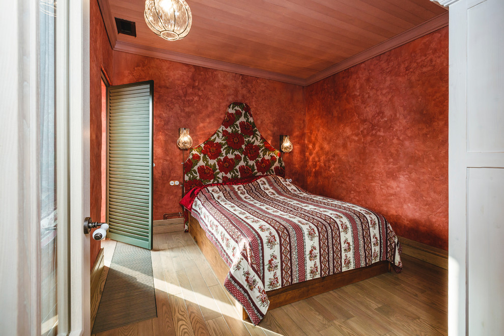 This is an example of a traditional guest bedroom in Other with light hardwood floors, red walls and no fireplace.
