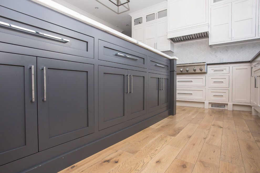 Eat-in kitchen - mid-sized transitional l-shaped medium tone wood floor eat-in kitchen idea in Baltimore with an undermount sink, shaker cabinets, white cabinets, marble countertops, white backsplash, marble backsplash, stainless steel appliances and an island