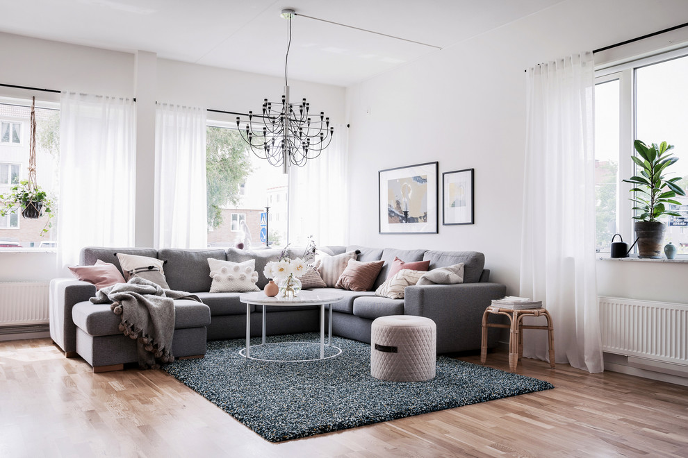 Photo of a scandinavian living room in Gothenburg with white walls, light hardwood floors and beige floor.