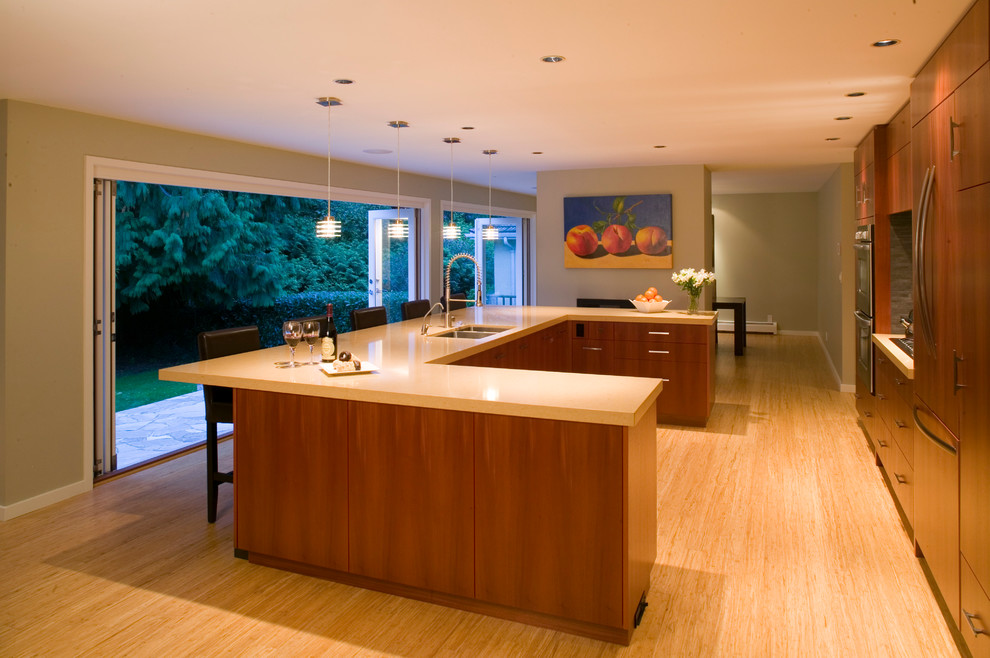 Photo of a contemporary u-shaped open plan kitchen in Vancouver with an undermount sink, flat-panel cabinets, medium wood cabinets, quartz benchtops, grey splashback, stone tile splashback and panelled appliances.