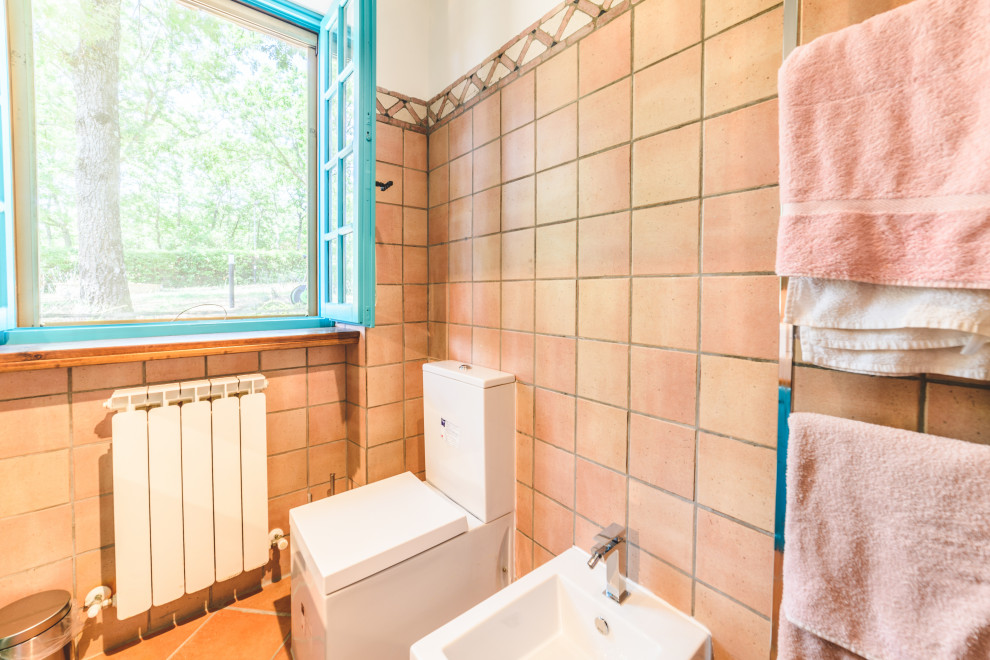 This is an example of a small modern 3/4 bathroom in Other with louvered cabinets, turquoise cabinets, a corner shower, a one-piece toilet, pink tile, ceramic tile, pink walls, terra-cotta floors, a vessel sink, limestone benchtops, orange floor, a hinged shower door and pink benchtops.