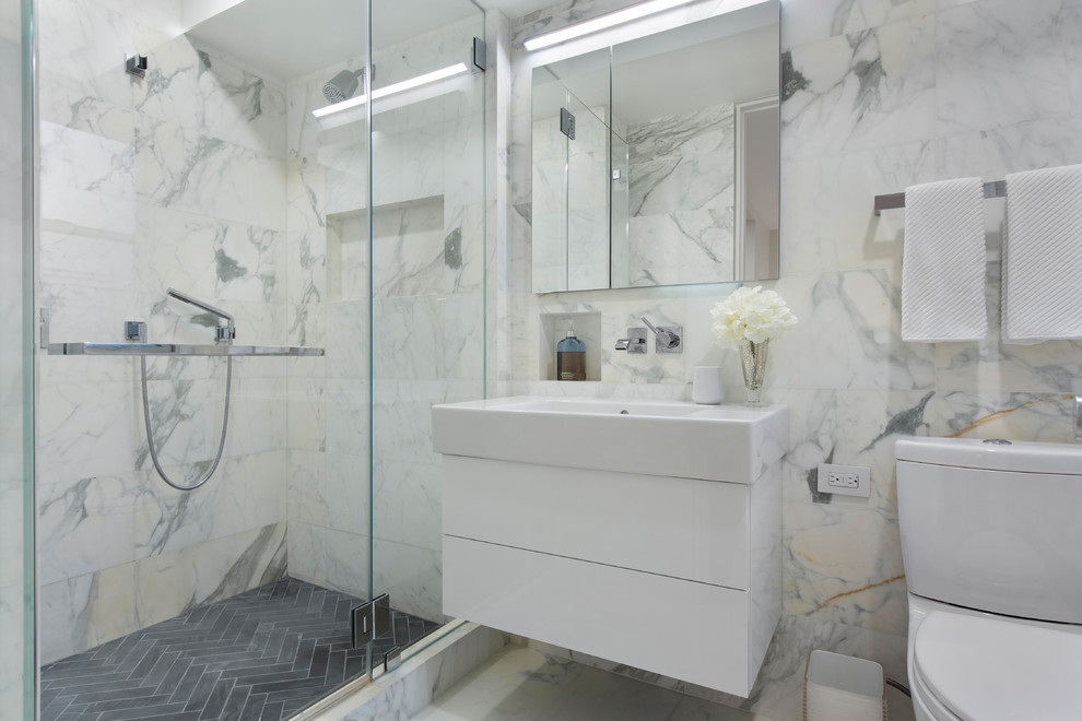 Design ideas for a mid-sized contemporary master bathroom in New York with an alcove shower, marble, marble floors, a hinged shower door, flat-panel cabinets, white cabinets, a two-piece toilet, white tile, white walls, a console sink and white floor.