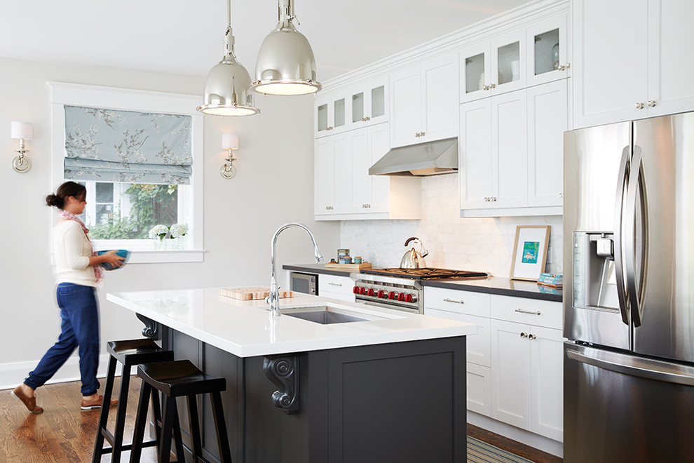 Beach style kitchen in Toronto with an undermount sink, shaker cabinets, white cabinets, white splashback, stainless steel appliances, medium hardwood floors and with island.