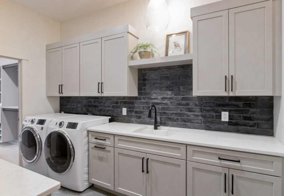 Exempel på en klassisk vita parallell vitt tvättstuga enbart för tvätt, med släta luckor, vita skåp, bänkskiva i kvarts, svart stänkskydd, stänkskydd i tunnelbanekakel, vita väggar, klinkergolv i keramik, en tvättmaskin och torktumlare bredvid varandra och grått golv