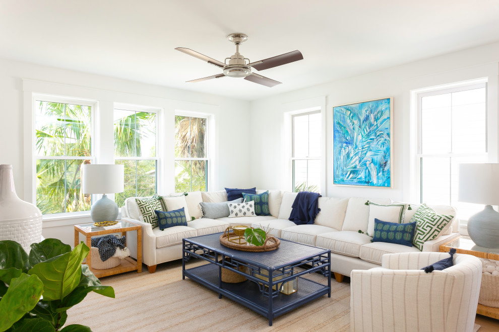 Inspiration for a mid-sized tropical open concept living room in Charleston with white walls, light hardwood floors and a wall-mounted tv.