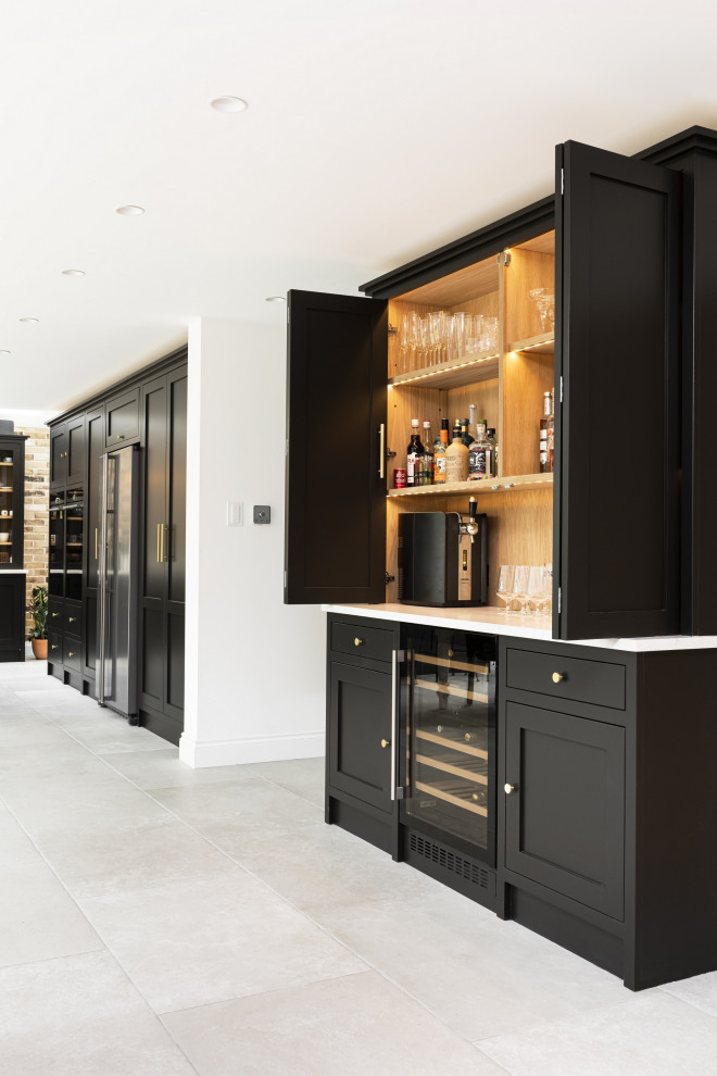 Large traditional single-wall eat-in kitchen in London with a farmhouse sink, shaker cabinets, black cabinets, quartzite benchtops, black appliances, porcelain floors, with island, grey floor and white benchtop.