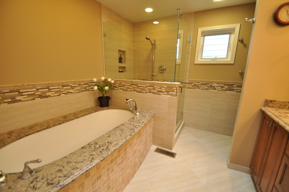 Design ideas for a mid-sized traditional master bathroom in Seattle with an undermount sink, raised-panel cabinets, medium wood cabinets, granite benchtops, an undermount tub, a corner shower, a two-piece toilet, beige tile, porcelain tile, beige walls and porcelain floors.