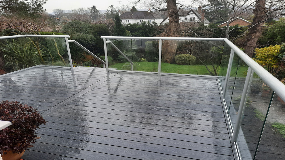 Imagen de terraza planta baja minimalista de tamaño medio en patio trasero con barandilla de vidrio