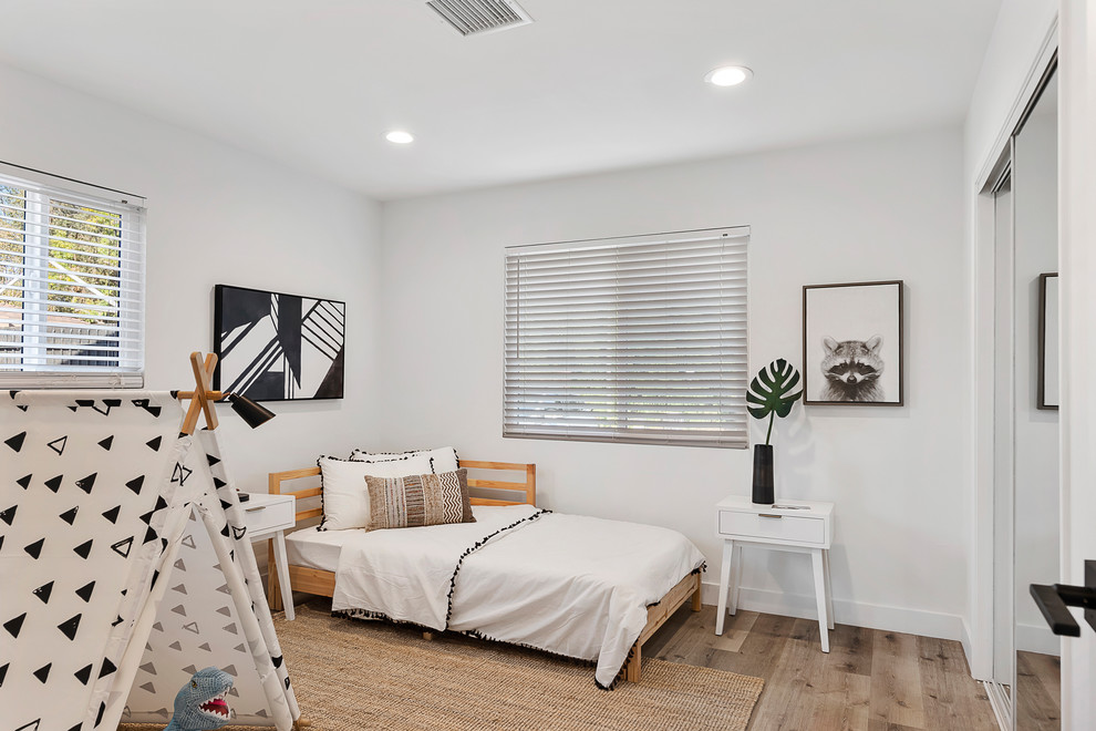 Contemporary gender-neutral kids' bedroom in Los Angeles with white walls, medium hardwood floors and brown floor for kids 4-10 years old.
