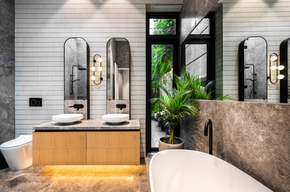 Design ideas for a contemporary bathroom in Melbourne with flat-panel cabinets, medium wood cabinets, a freestanding tub, white tile, a vessel sink, grey floor, grey benchtops, a double vanity and a floating vanity.