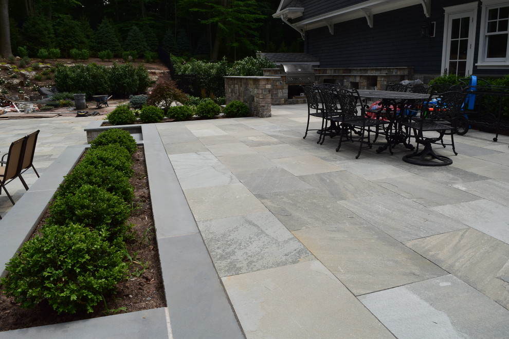 Large traditional patio in New York with an outdoor kitchen, natural stone pavers and no cover.