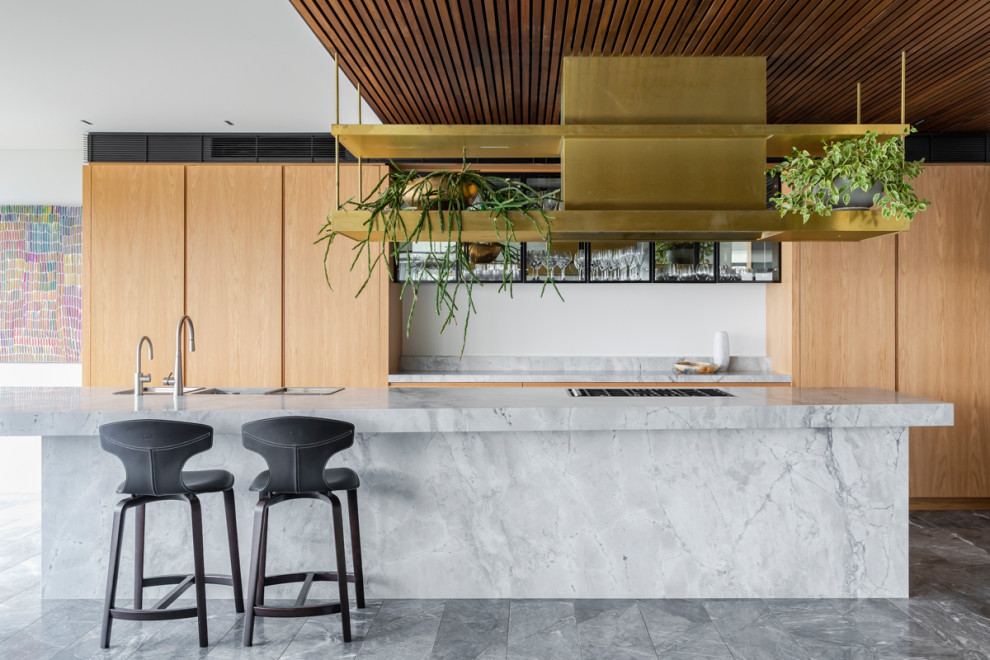 This is an example of a large contemporary galley kitchen in Sydney with a double-bowl sink, flat-panel cabinets, medium wood cabinets, panelled appliances, with island, grey floor and grey benchtop.