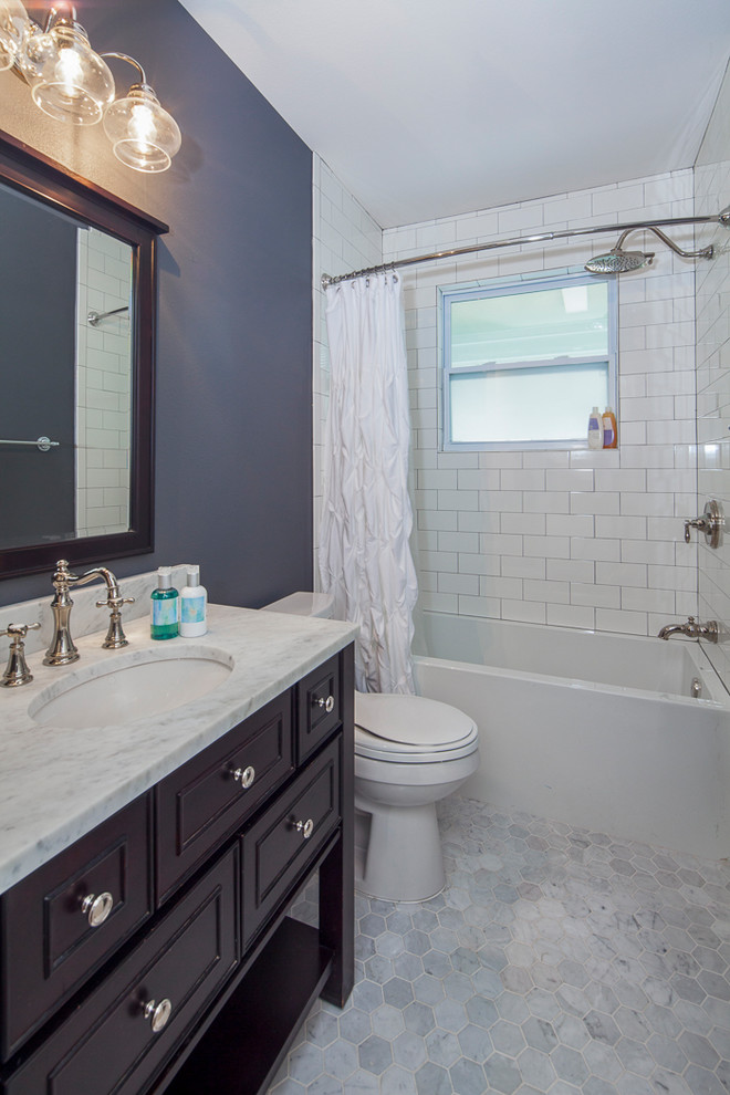 Design ideas for a mid-sized arts and crafts bathroom in Austin with furniture-like cabinets, brown cabinets, a corner tub, a two-piece toilet, white tile, ceramic tile, grey walls, marble floors, an undermount sink, marble benchtops, grey floor and a hinged shower door.
