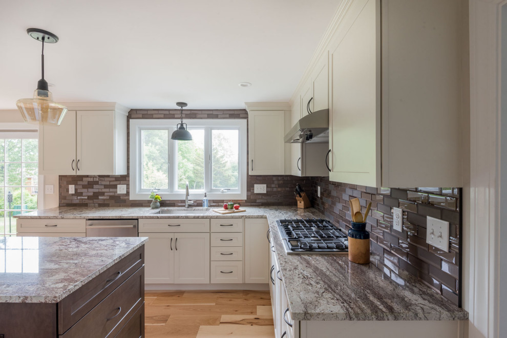Mid-sized transitional u-shaped light wood floor and brown floor eat-in kitchen photo in Boston with an undermount sink, shaker cabinets, white cabinets, granite countertops, brown backsplash, glass tile backsplash, stainless steel appliances, an island and multicolored countertops