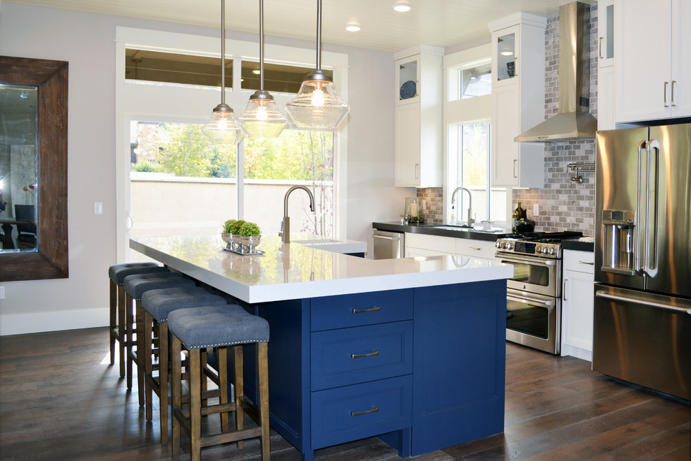 Inspiration for a mid-sized transitional galley open plan kitchen in Salt Lake City with an undermount sink, shaker cabinets, white cabinets, quartz benchtops, grey splashback, mosaic tile splashback, stainless steel appliances, medium hardwood floors, with island and brown floor.