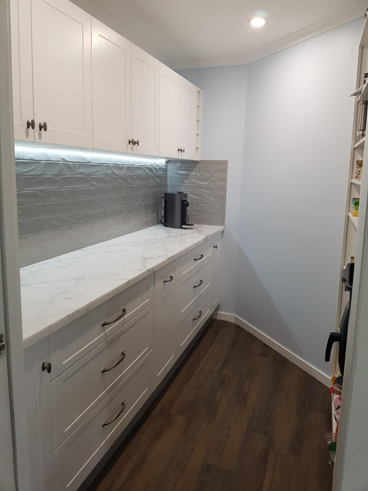 Large traditional galley kitchen pantry in Sunshine Coast with an undermount sink, shaker cabinets, white cabinets, marble benchtops, white splashback, subway tile splashback, stainless steel appliances, with island and white benchtop.