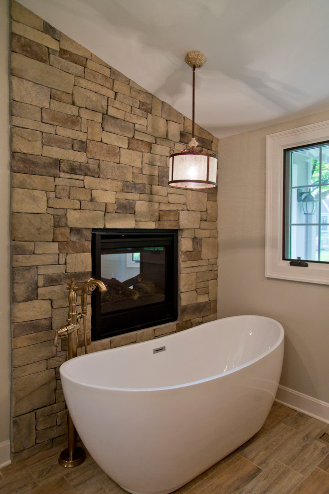 This is an example of a large country master bathroom in Kansas City with furniture-like cabinets, medium wood cabinets, a freestanding tub, an alcove shower, grey walls, medium hardwood floors, an undermount sink, granite benchtops and brown floor.