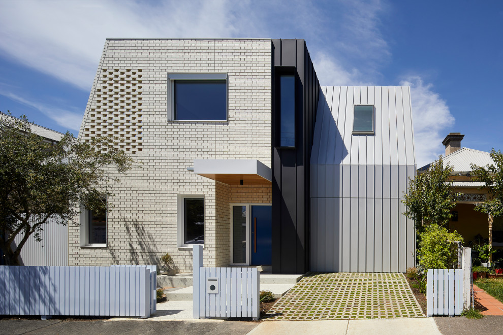 This is an example of a mid-sized contemporary two-storey brick multi-coloured house exterior in Melbourne with a flat roof and a metal roof.