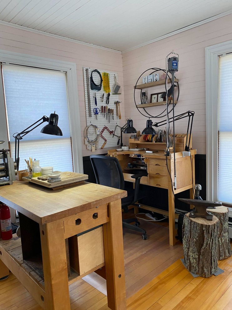 Industriell inredning av ett litet hemmastudio, med rosa väggar, mellanmörkt trägolv och ett fristående skrivbord