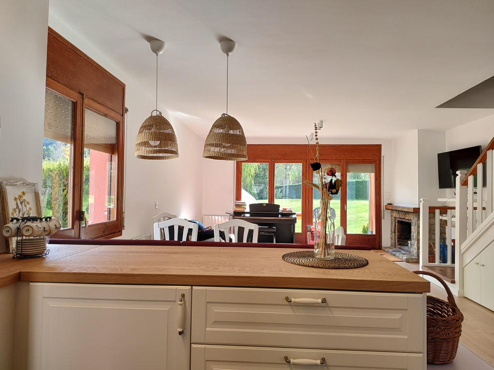 Стильный дизайн: кухня-столовая среднего размера в стиле неоклассика (современная классика) с белыми стенами, светлым паркетным полом, стандартным камином, фасадом камина из камня и коричневым полом - последний тренд
