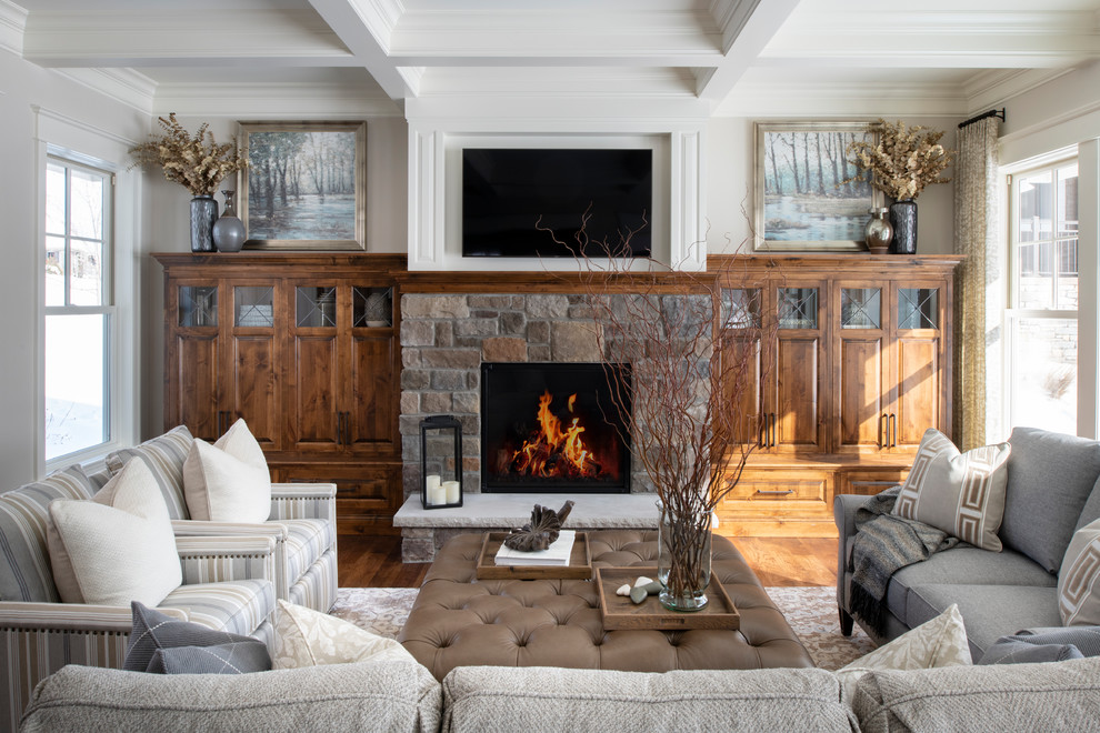 Photo of a traditional living room in Minneapolis with grey walls, medium hardwood floors, a standard fireplace, a stone fireplace surround and brown floor.