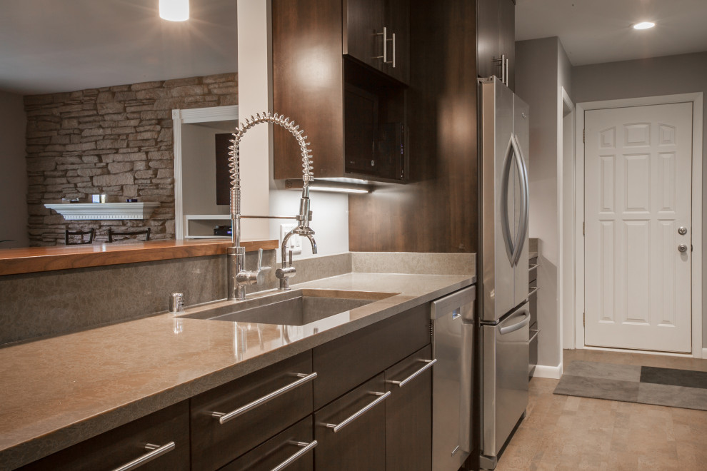 Example of a transitional galley cork floor and gray floor eat-in kitchen design with an undermount sink, flat-panel cabinets, dark wood cabinets, quartz countertops, mosaic tile backsplash, stainless steel appliances and a peninsula