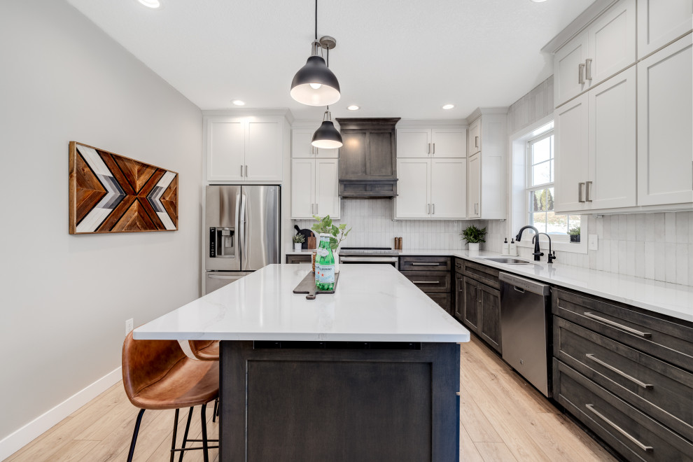 Inspiration for a large transitional l-shaped vinyl floor and brown floor eat-in kitchen remodel in Other with a double-bowl sink, shaker cabinets, white cabinets, quartz countertops, white backsplash, ceramic backsplash, stainless steel appliances, an island and white countertops