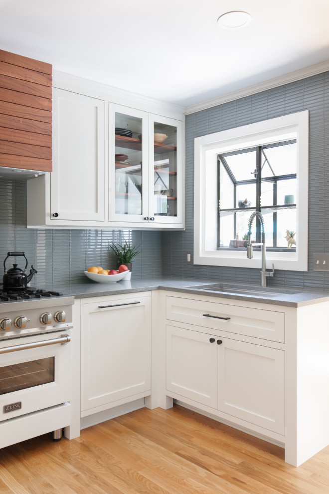 Eat-in kitchen - mid-sized transitional u-shaped light wood floor and brown floor eat-in kitchen idea in Austin with an undermount sink, shaker cabinets, white cabinets, quartz countertops, blue backsplash, glass tile backsplash, stainless steel appliances, no island and gray countertops