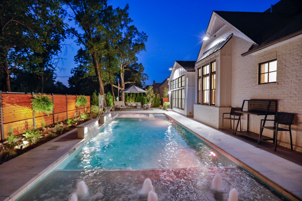 Modelo de piscina alargada tradicional de tamaño medio rectangular en patio trasero con privacidad y adoquines de piedra natural
